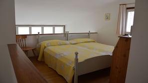 A bedroom with a bed, a chair, a window, and a door.