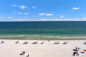 A beach with white sand, clear blue water, and a few umbrellas. - Summer House 806B | Sleeps 10 | 3BR | 2BA (Orange Beach)