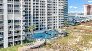 A high-rise hotel with multiple balconies, a central swimming pool, and a boardwalk with beach access. - Summer House 806B | Sleeps 10 | 3BR | 2BA (Orange Beach)