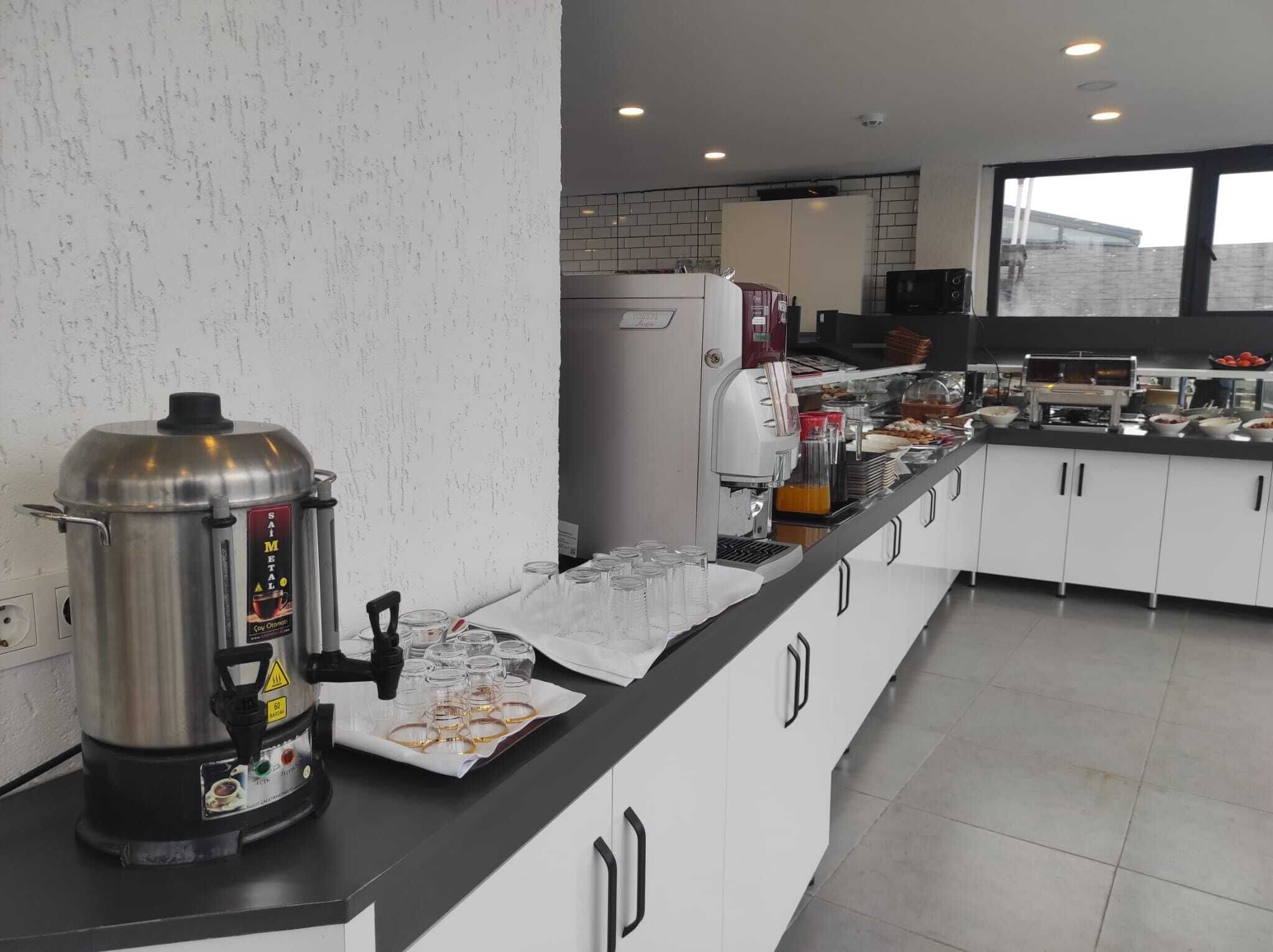 A modern kitchen with a coffee station, a large pot, and a refrigerator.