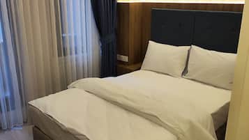 Una habitación de hotel con una cama grande, un cabecero de madera y una mesita de noche con una lámpara.
