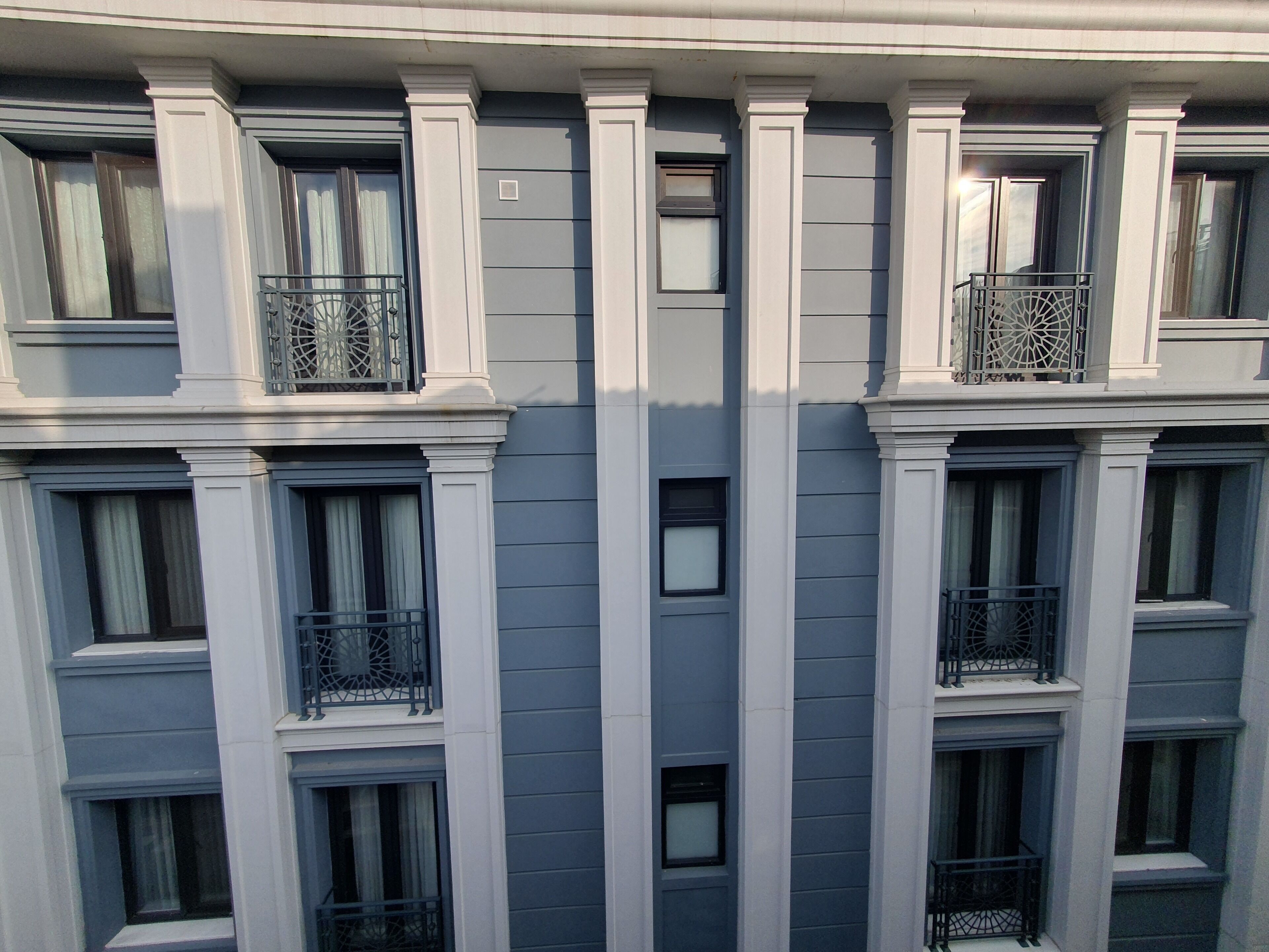 A multi-story building with a symmetrical facade, featuring evenly spaced windows and balconies with metal railings.