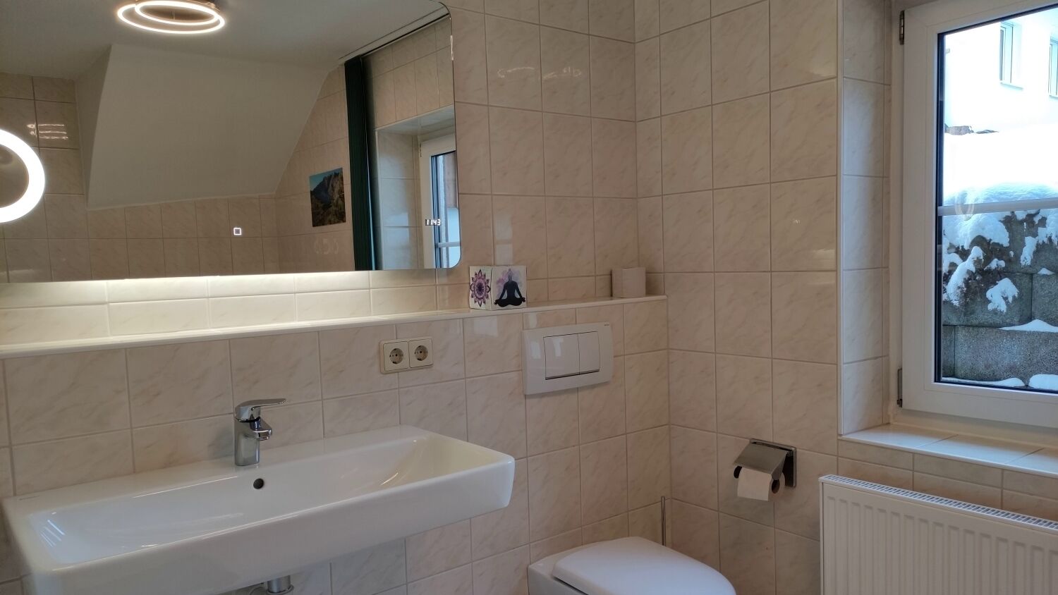 Une salle de bain moderne avec un grand miroir, un lavabo et des toilettes.
