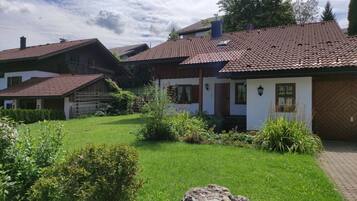 A traditional chalet-style house with a tiled roof, surrounded by a well-maintained garden.