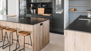 A modern kitchen with a central island, bar stools, and built-in appliances. - Casa Belvedere - Villa with fantastic views, completion January 2024! (Villaverde)
