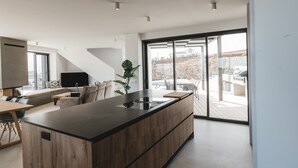 A modern kitchen with a large island, built-in appliances, and a sliding glass door leading to an outdoor patio. - Casa Belvedere - Villa with fantastic views, completion January 2024! (Villaverde)