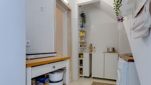 A compact kitchen with white cabinets, a wooden countertop, and a washing machine. - Charming house for 6 persons at downtown Faro (Faro)