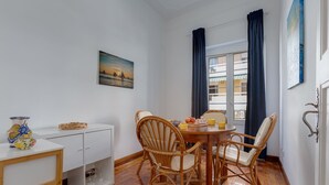 A dining area with a round table, four wicker chairs, a white cabinet, and a painting of a sunset. - Charming house for 6 persons at downtown Faro (Faro)