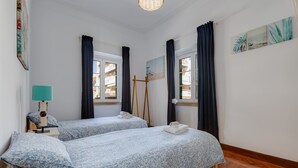 A room with two beds, a standing lamp, a painting, and a window with curtains. - Charming house for 6 persons at downtown Faro (Faro)