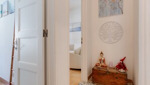 A hallway with a wooden chest of drawers, a Buddha statue, and a tree wall art piece. - Charming house for 6 persons at downtown Faro (Faro)