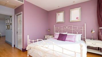 A bedroom with a white metal bed frame, a purple wall, and two bedside tables with lamps.