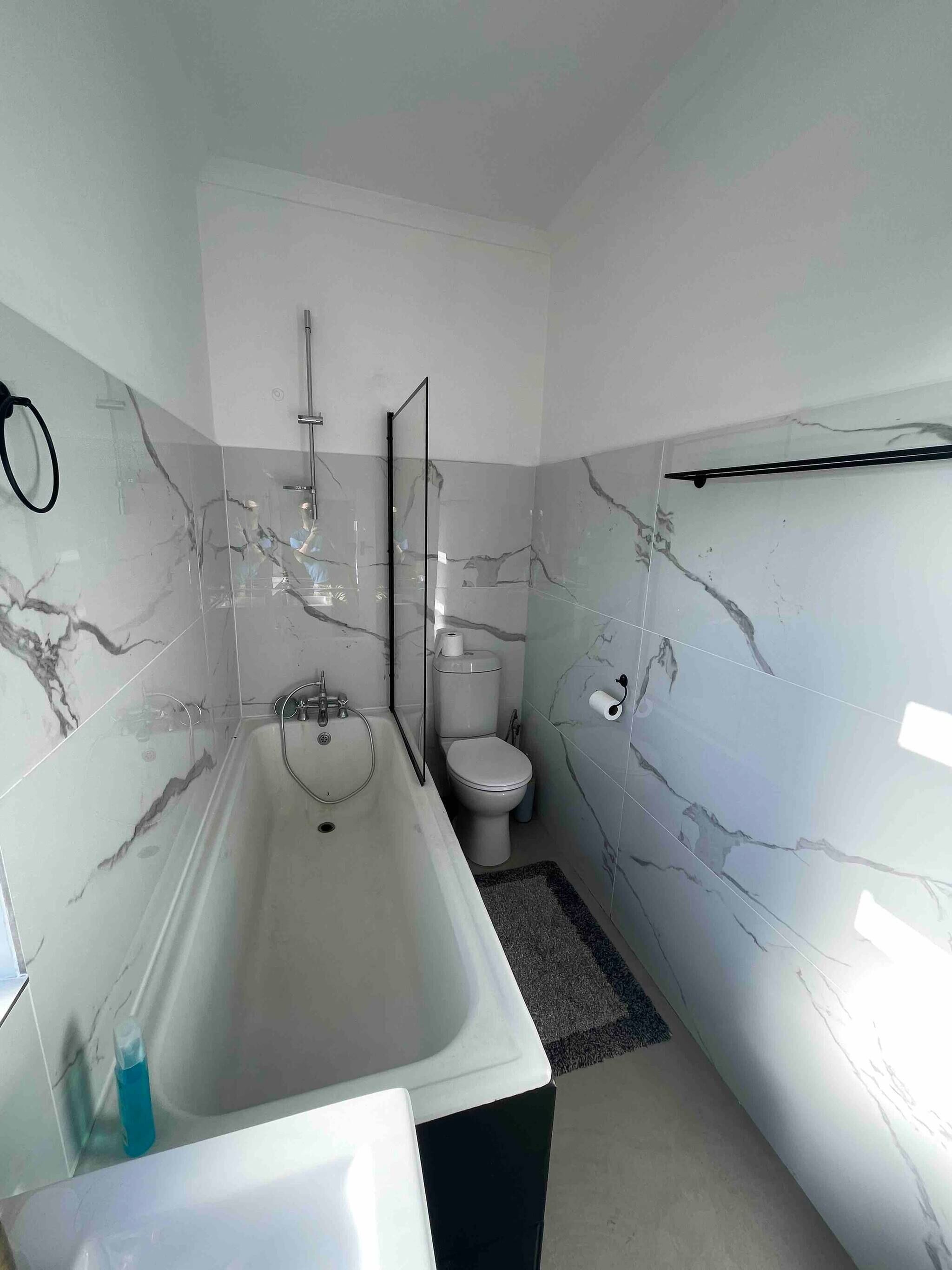 Une salle de bain moderne avec une baignoire sur pieds, des toilettes et une douche à parois de verre.