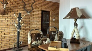 A room with a brick wall, a wooden table, and a lamp. - JBayholiday (Jeffreys Bay)