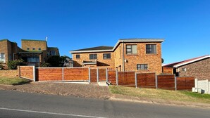 A residential area with a brick house, a gated driveway, and a clear sky. - JBayholiday (Jeffreys Bay)