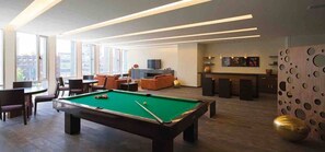 A modern living room with a pool table, seating area, and a bar.