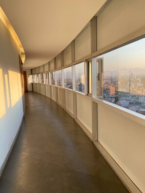A long, empty corridor with large windows offering a city view.