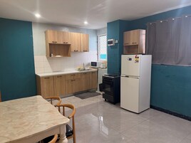 Uma cozinha compacta com armários de madeira, geladeira branca, micro-ondas, fogão e uma mesa de jantar com cadeiras.