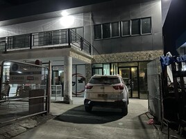 Um carro branco estacionado em frente a um edifício com uma placa que diz 'TOTA'.