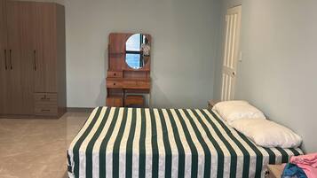 A bedroom with a bed, a dresser, a mirror, and a wardrobe.
