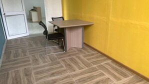 A small room with a table and a chair, a door, and a yellow wall. - Captivating 1-bed Studio in Honiara (Honiara)