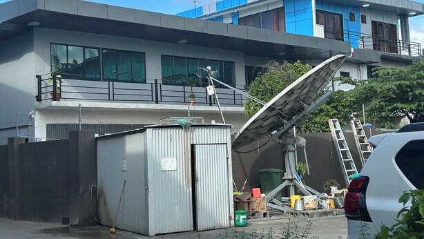 A modern building with a satellite dish, a small shed, and a white car parked nearby. - Captivating 1-bed Studio in Honiara (Honiara)