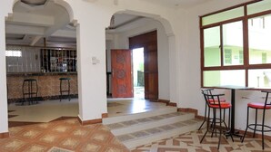 A spacious interior with a kitchen area, a dining area with bar stools, and a patterned floor. - Greenyard Resort Mtwapa (Mtwapa)