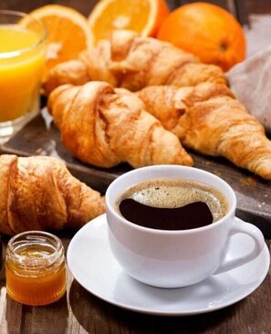 A breakfast setting with croissants, a cup of coffee, a glass of orange juice, and a jar of honey. - Auberge de l'Ours (Vex)