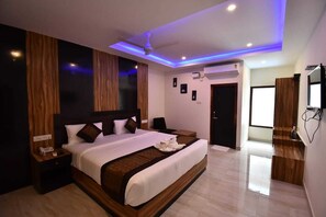 A modern hotel room with a large bed, wooden headboard, and a ceiling fan. - Hotel SRI KPN (Port Blair)