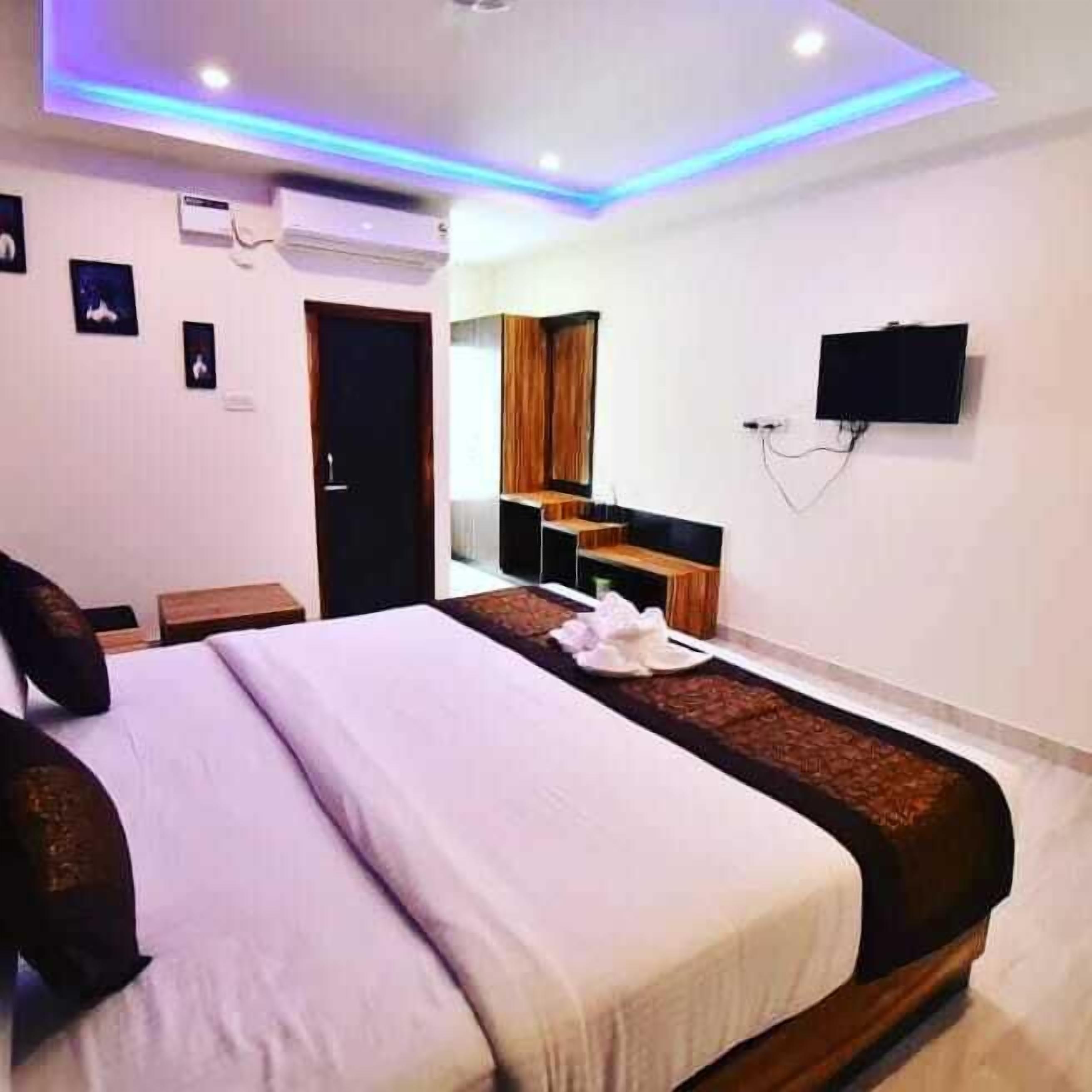 A hotel room with a bed, a desk, a TV, and a wardrobe.