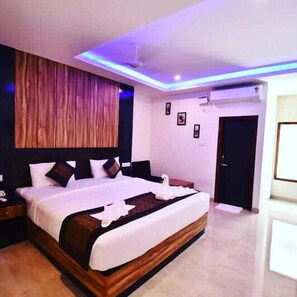 A modern hotel room with a large bed, wooden headboard, and a ceiling with blue LED lighting. - Hotel SRI KPN (Port Blair)