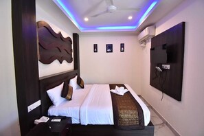Una camera d'albergo con un letto, una TV a schermo piatto fissata al muro e una ventola a soffitto.