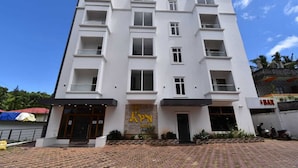 A multi-story hotel with a modern design, featuring balconies on each floor, a prominent entrance with a sign, and a paved driveway. - Hotel SRI KPN (Port Blair)
