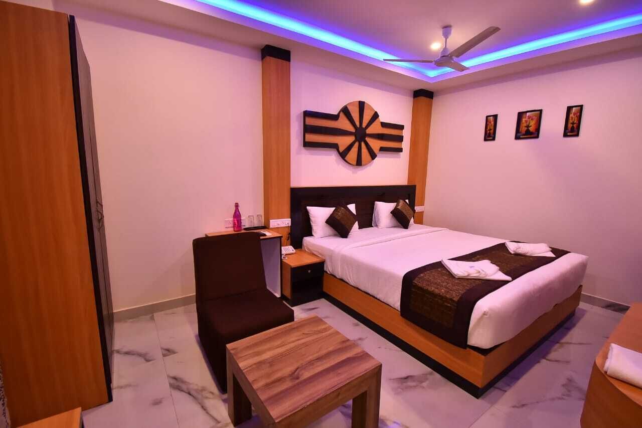 A hotel room with a large bed, a desk, a chair, and a small table.
