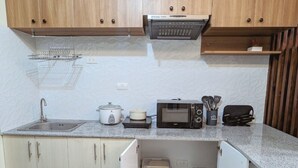 Eine kleine Küche mit Holzausstattung, einer Mikrowelle, einem Wasserkocher und einem Spülbecken.