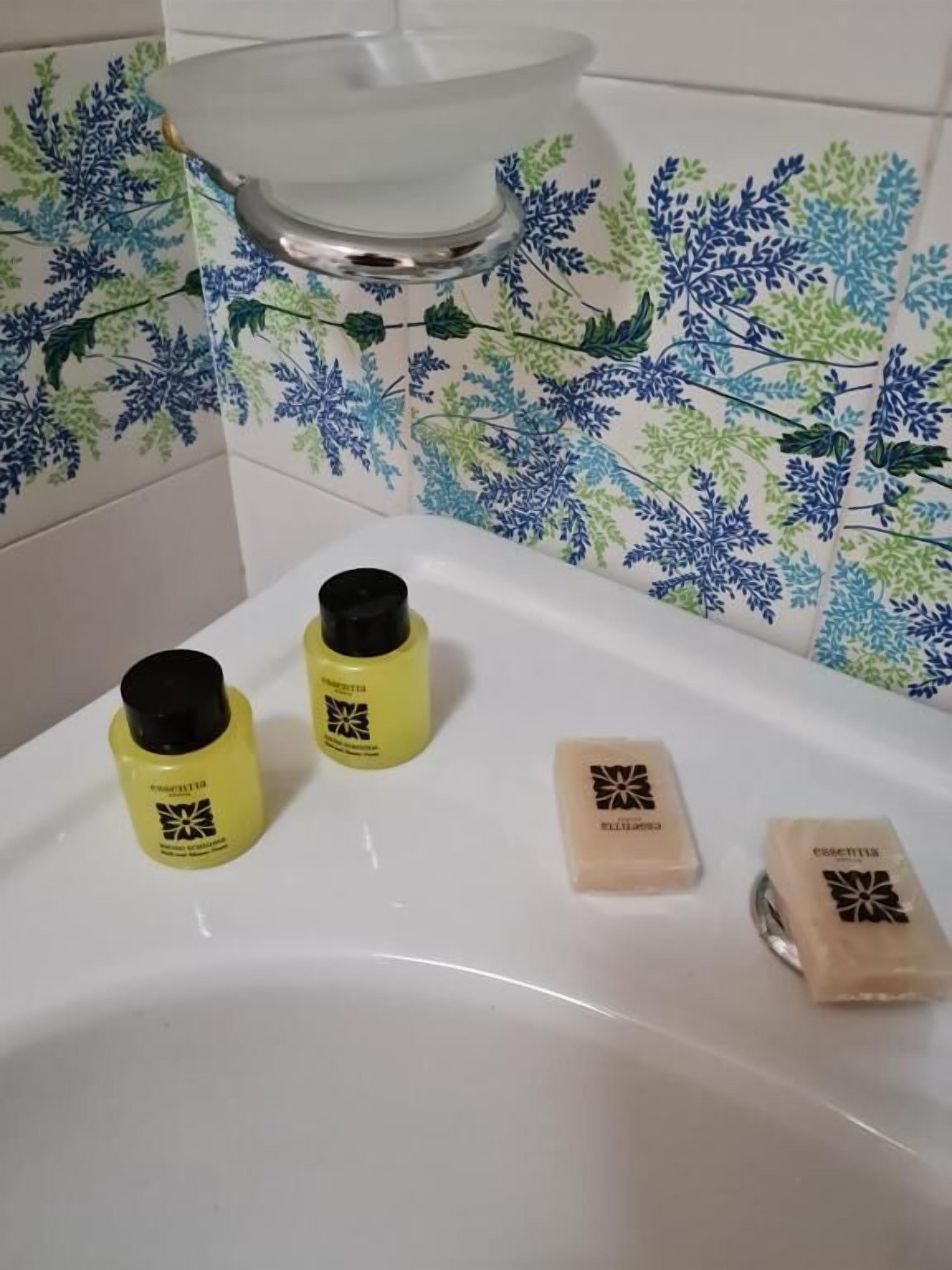 A bathroom with a white sink, two yellow bottles, and two soap bars on the counter.
