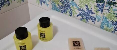 A bathroom with a white sink, two yellow bottles, and two soap bars on the counter.