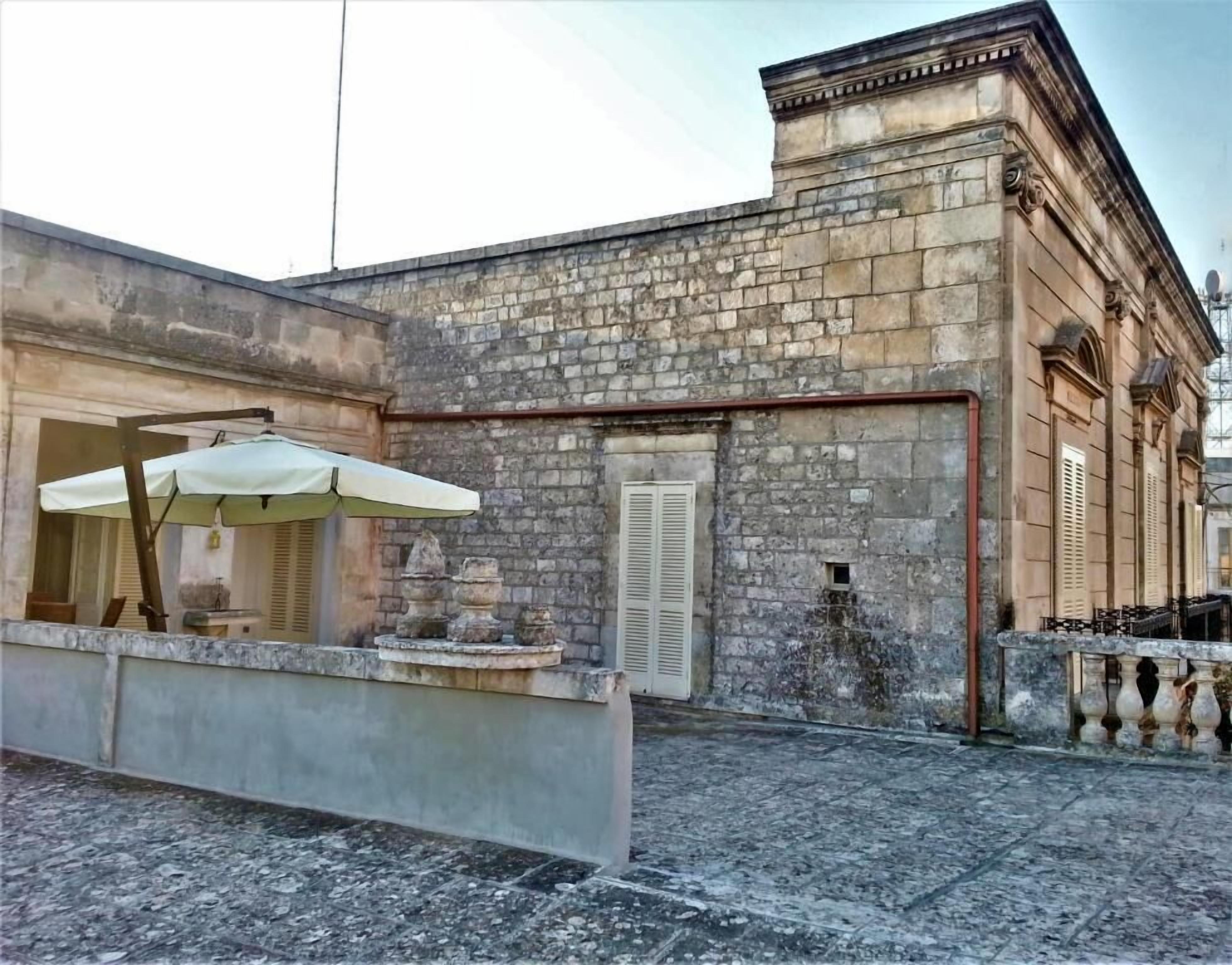 A stone building with a courtyard, a white umbrella, and a small fountain.