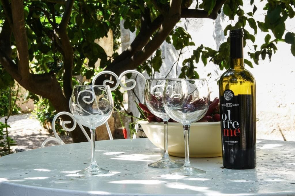 A table with three wine glasses and a bottle of wine.