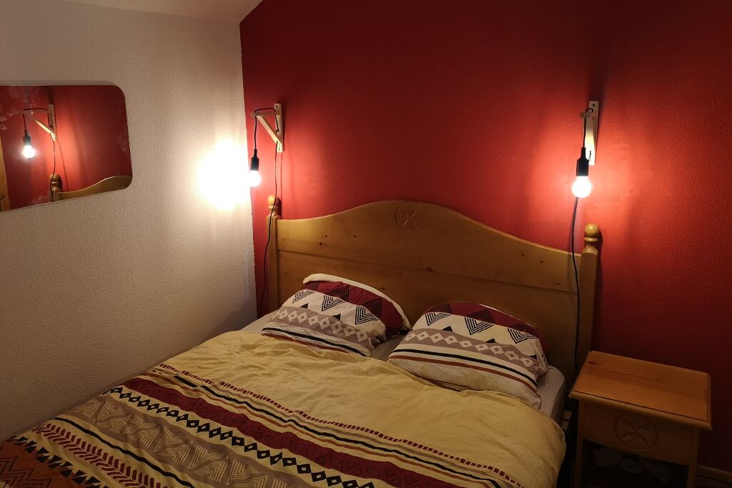 Een bed met beddengoed met een patroon, een houten hoofdbord en bedlampen.