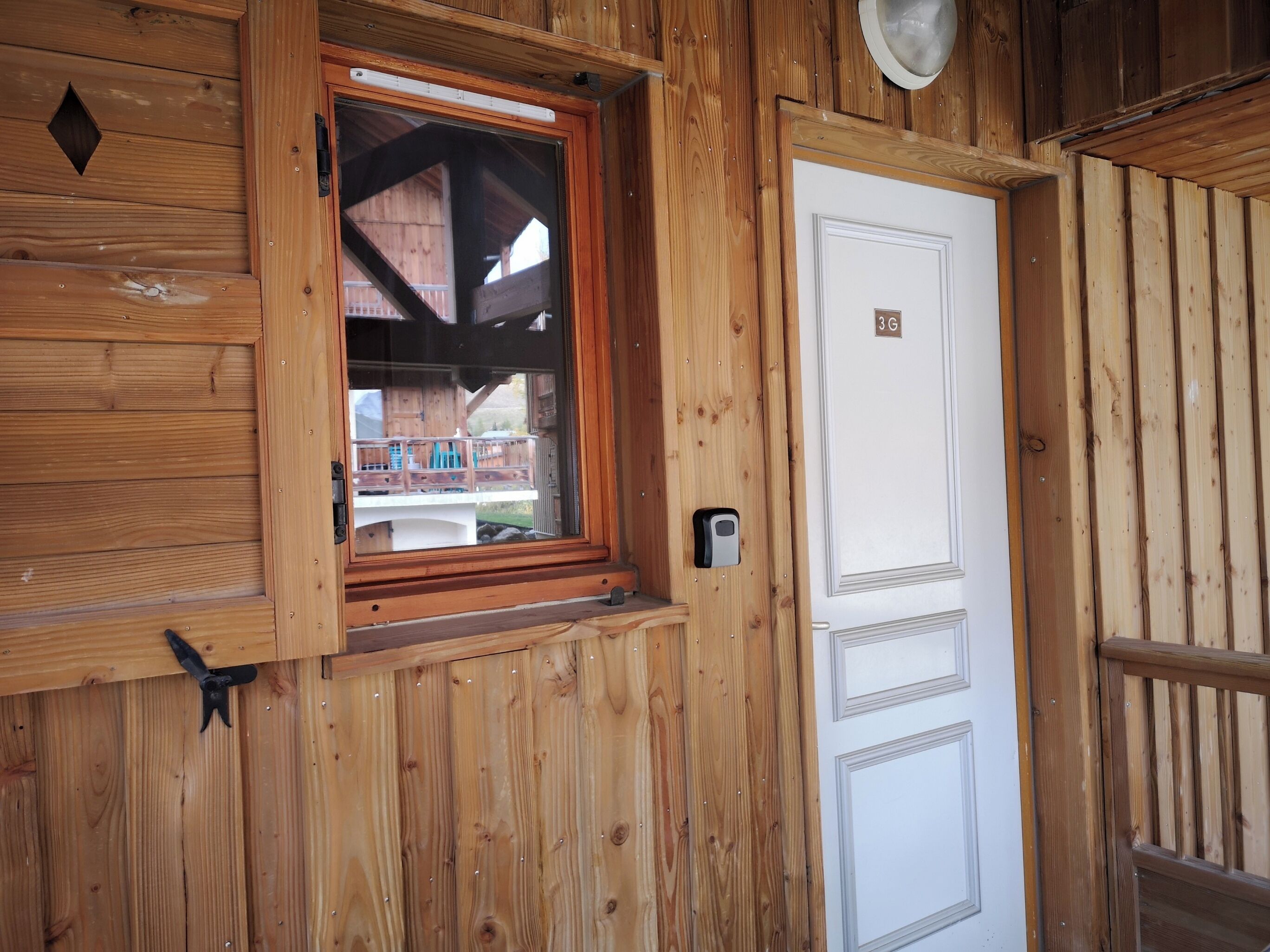 A wooden cabin with a window, a white door, and a small window with a sensor.