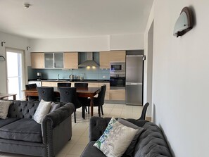 A modern living room with a grey sofa set and a dining area with a wooden table and chairs.