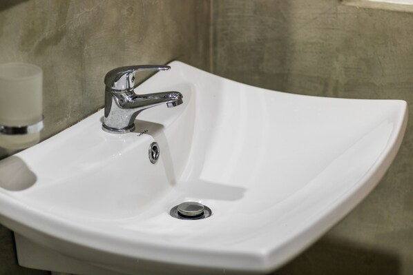 A white sink with a chrome faucet and a drain.