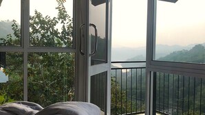 A bedroom with a large window and a balcony.