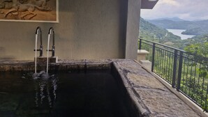 A hot tub with a view of a lake and mountains.