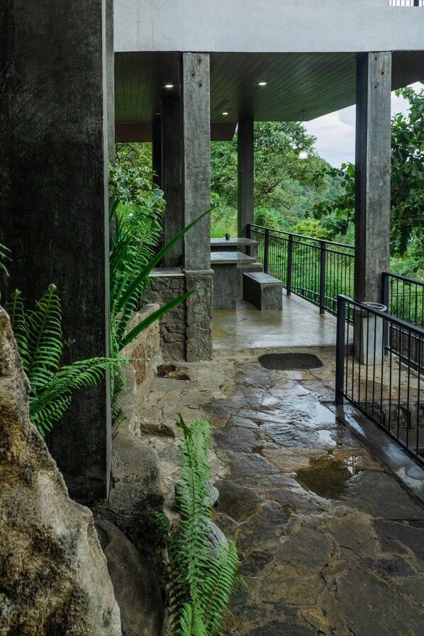 A stone pathway leading to a covered area with benches and a railing.