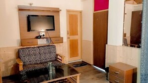 Un espai habitable compacte amb un sofà, una taula petita, un televisor muntat sobre un moble de fusta, un armari i un mirall.