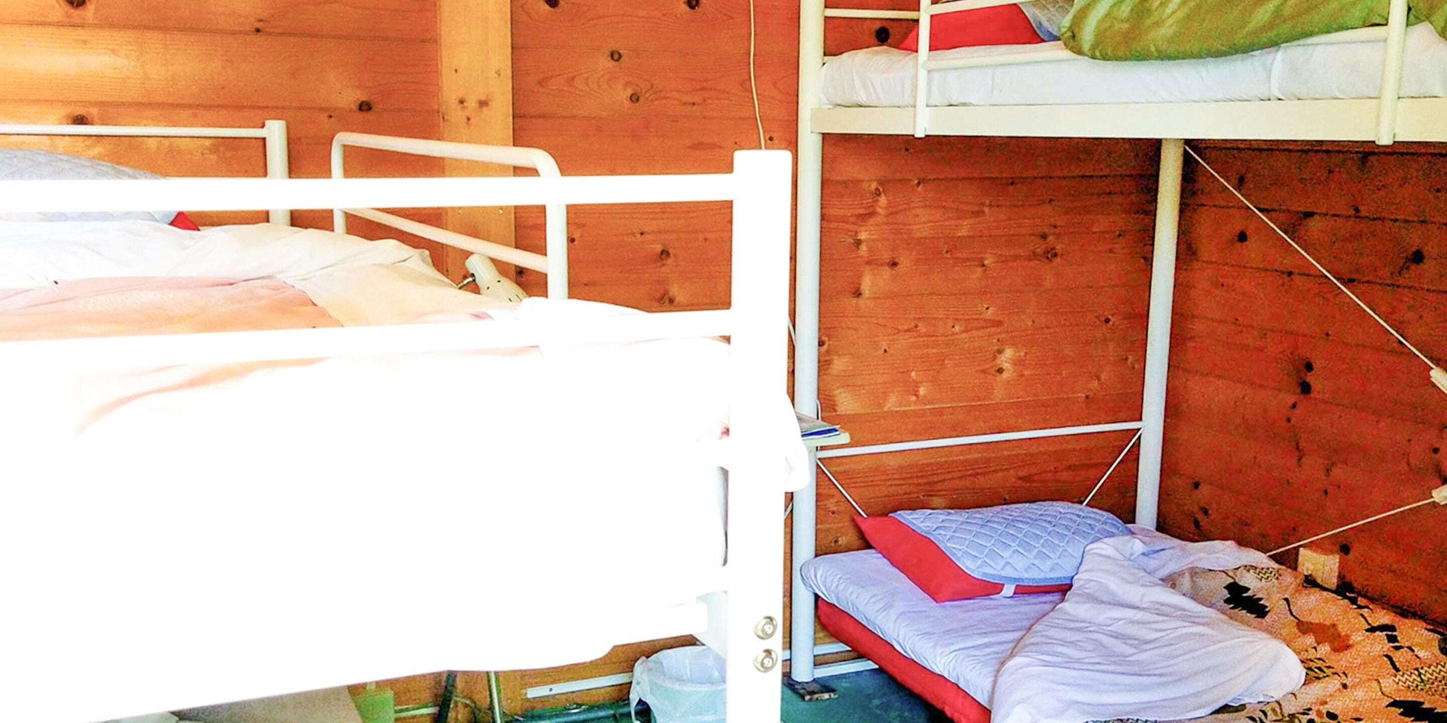 A bunk bed room with wooden walls and white metal railings.