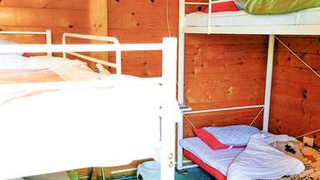 A bunk bed room with wooden walls and white metal railings.