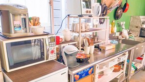 A kitchen with a microwave, coffee maker, and various kitchen utensils. - Forest Cottage Kesennuma (Kesennuma)