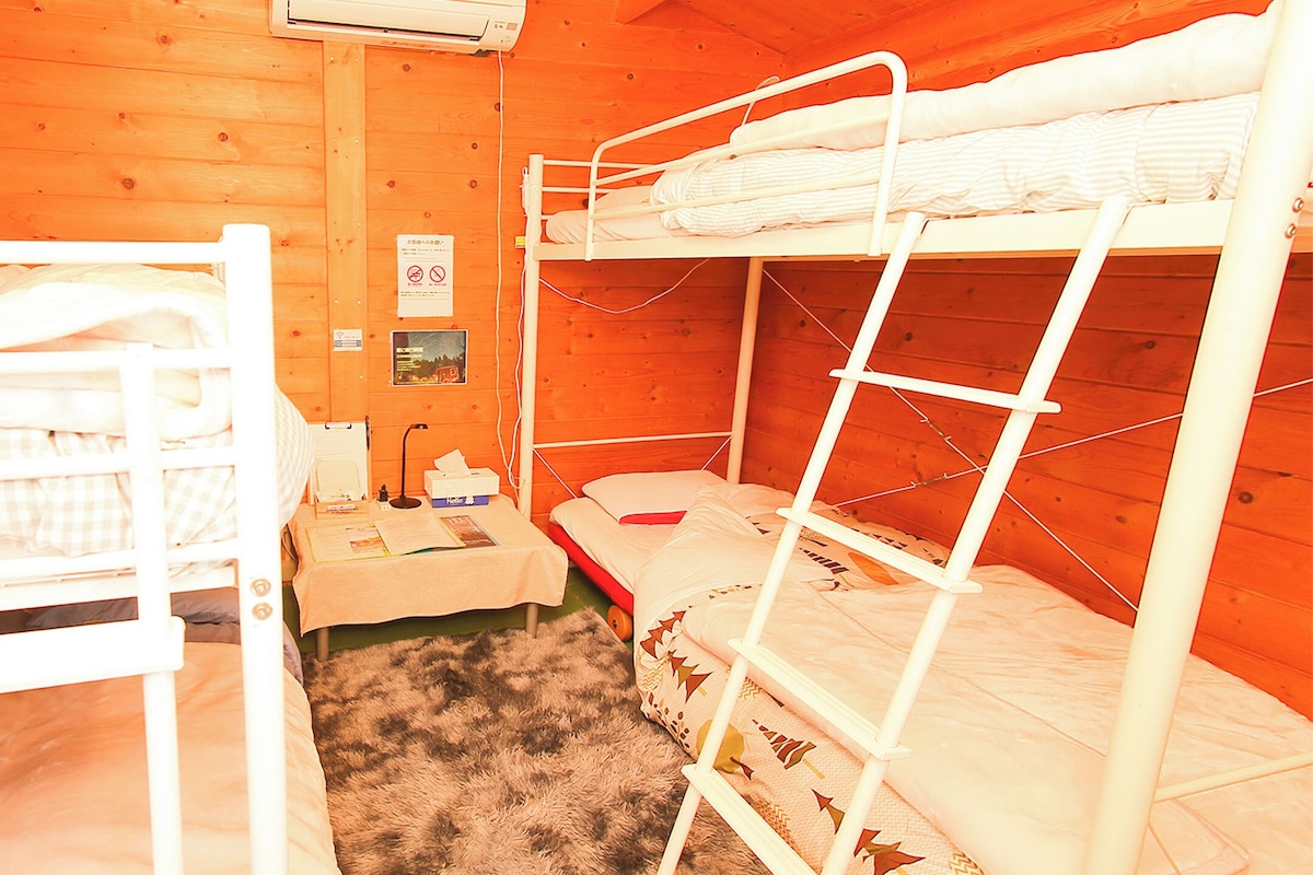 Dormitorio con literas, paredes de madera, un escritorio pequeño y una alfombra.